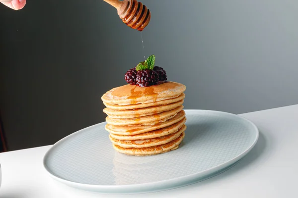 新鮮なブルーベリーとアメリカのパンケーキ ラズベリーと蜂蜜 健康的な朝の朝食 ブラックベリーと黄金の蜂蜜と自家製のアメリカのパンケーキ 健康的な朝の朝食 — ストック写真