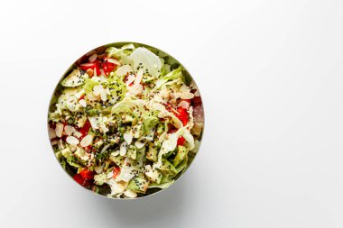 Vegetable salad with iceberg lettuce, romaine and radicchio salad in a metal bowl on white background. Top view with copy space. Avocado, cucumber, tomatoes cherry, sesame seeds, flax seeds, olive oil