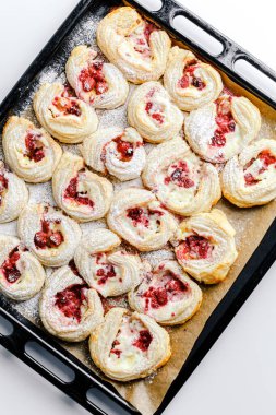 Fresh delicious puff pastry with sweet berries.  Puff pastry tart with raspberry and cream cheese mascarpone. Cream filling and sweet berry topping. Close-up baked goods. hands transfer hot buns with a baking oven on a plate.