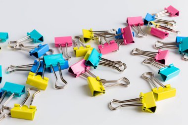 Colorful metal binder clips - office supply on light grey and white background.