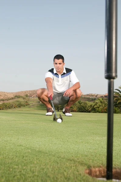 Male golfer crouching while aiming at ball — Stock Photo, Image