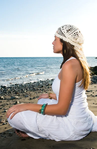 Девушка в белом платье сидит на пляже — стоковое фото