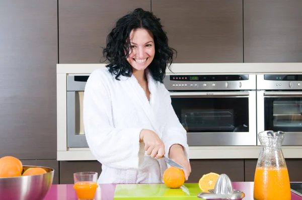 Jovem mulher feliz cortando laranja — Fotografia de Stock