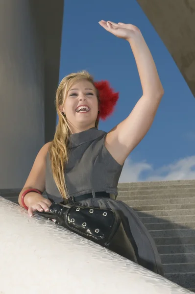 Young woman on a staircase waving — Stock Photo, Image