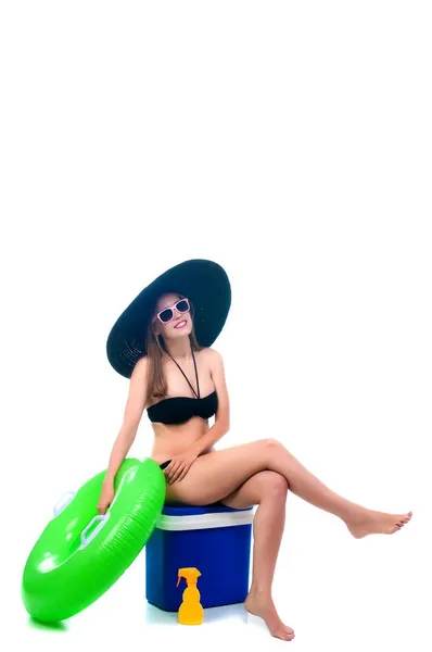 Beautiful young woman sits on a cooler bag with a large rubber ring — Stock Photo, Image