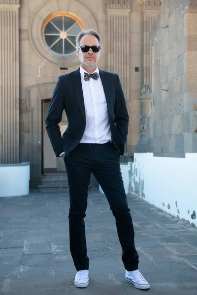 Attractive mature man in tuxedo walking in the city