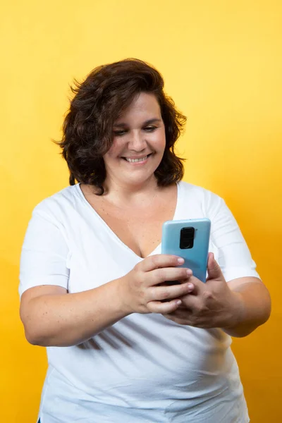 Sarı Arka Planda Teknolojiyi Kullanan Kıvrımlı Kadın — Stok fotoğraf