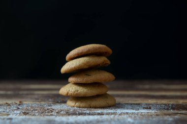 Koyu bir ahşap masaya istiflenmiş kurabiye dağı.