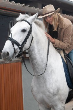 Ahırdaki kadın binici koşuya çıkmadan önce ata binmiş.
