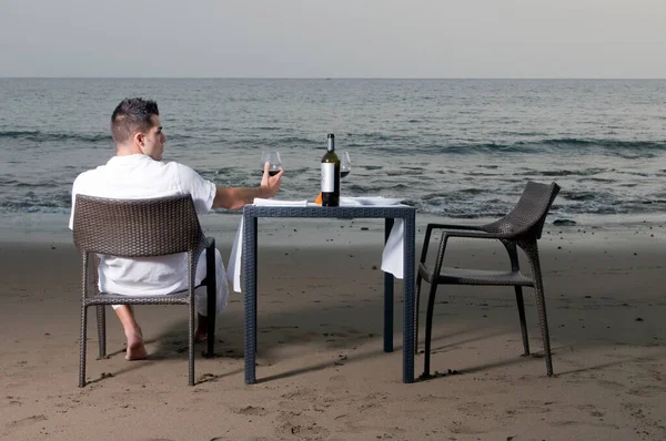 身穿白色衣服的年轻人等着在海滩上庆祝浪漫的晚餐 — 图库照片