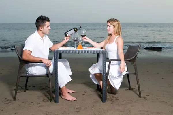 穿着白色衣服的年轻夫妇在海滩上庆祝浪漫的晚餐 — 图库照片