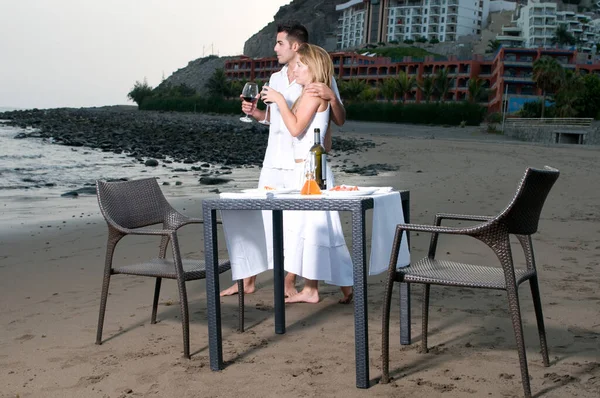 穿着白色衣服的年轻夫妇在海滩上庆祝浪漫的晚餐 — 图库照片