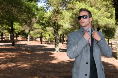 Tarlanın ortasında, çam ağaçlarının arasında paltosuyla zarif bir adam.