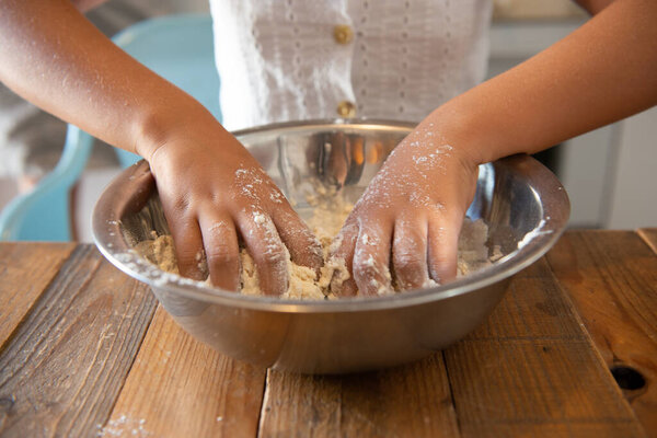African American girl in her home kitchen making a pastry dough