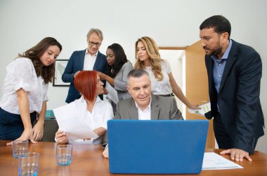 Business team of men and women in an office analyzing the evolution of the company