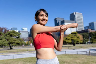 Sağlıklı bir kadın sabah erken saatlerde Tokyo şehir merkezinde koşuya hazırlanıyor. Gülümsedi ve eğlendi..