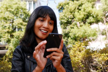 Akıllı telefon kullanan Asyalı bir iş kadını. Gülümsedi ve eğlendi..