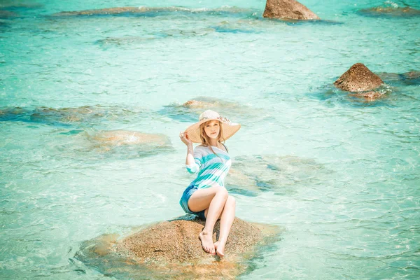 Mulher relaxante em uma pedra no oceano azul — Fotografia de Stock