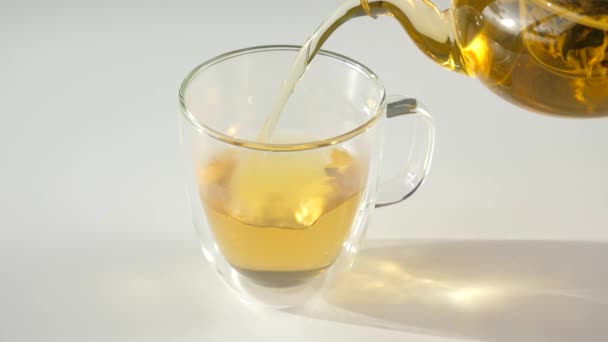 Close-up van hete groene thee gieten om dubbele wand glazen beker van glazen theepot — Stockvideo
