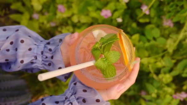 Női kéz tartó és forgó üveg alkoholos koktél, ökokapír szalma — Stock videók