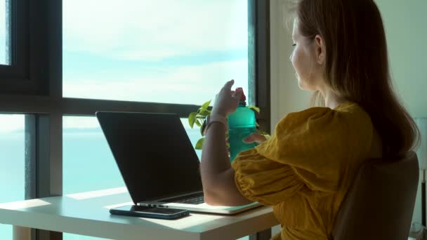 Jonge vrouw met behulp van laptop computer thuis en het drinken van helder zoet water — Stockvideo