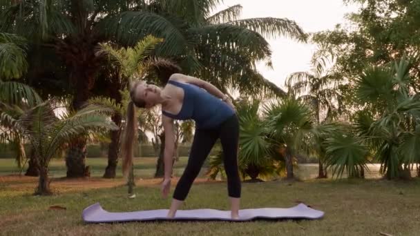 Junge Frau Steht Auf Yogamatte Und Macht Aufwärmgymnastik Tropical City — Stockvideo