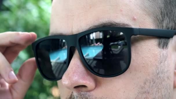 Man op zoek van onder zwarte zonnebril, toont verwond oog met ontsteking — Stockvideo