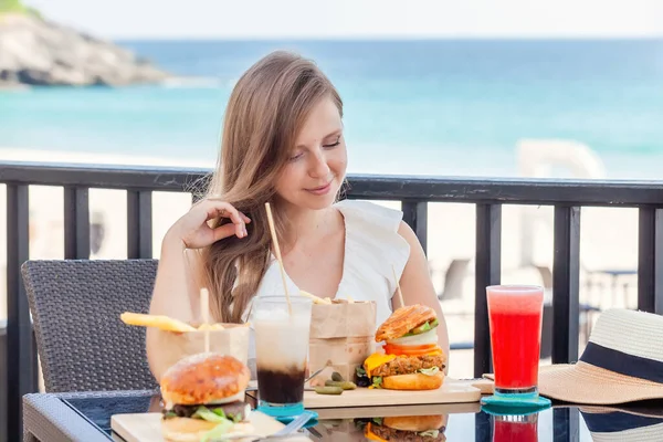 Mujer viajera con comida rápida, hamburguesas, café y jugos en el café al aire libre — Foto de Stock