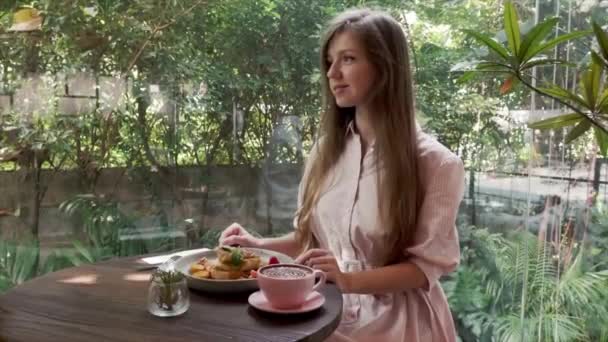 Frau mit Morgenessen in gemütlichem Restaurant mit Sonnenstrahlen bei sonnigem Tag — Stockvideo