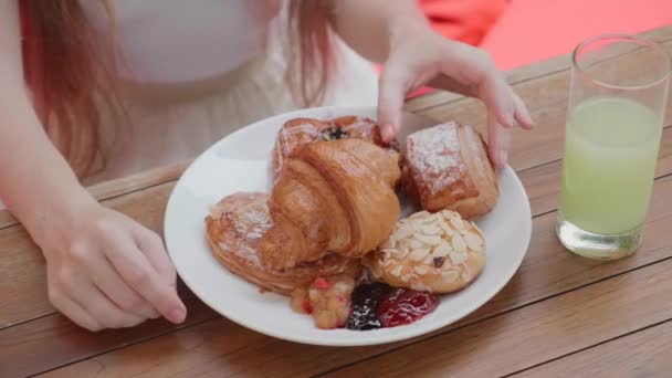 女の子のクローズアップ屋外カフェで新鮮なパンを食べます,ホテルで朝食 — ストック動画