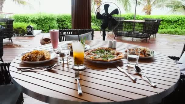 Стол с едой и коктейлями в ресторане на открытом воздухе в тропическом курорте или отеле — стоковое видео