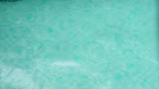 Lichte regen druipt op het heldere water in turquoise zwembad — Stockvideo