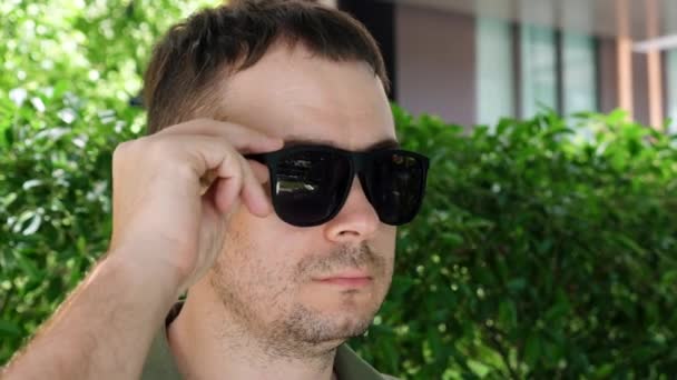 Unglücklicher ernster Mann versteckt rotes geschwollenes Auge mit Entzündung unter schwarzer Sonnenbrille — Stockvideo