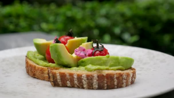 Beyaz tabakta ızgara kiraz domatesli taze avokado tostu. Sağlıklı yağlar — Stok video