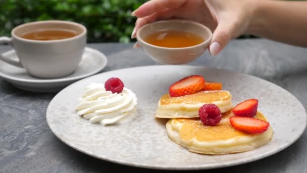 Wanita tangan menuangkan sirup maple di pancake Amerika dengan buah berry segar — Stok Video