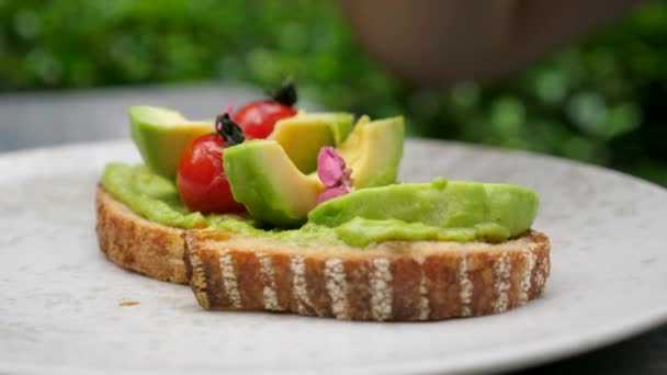 Vaření žitného chleba toast s rozmačkanou avokádovou pomazánkou, detailní záběr mužské kuchařské ruky — Stock video