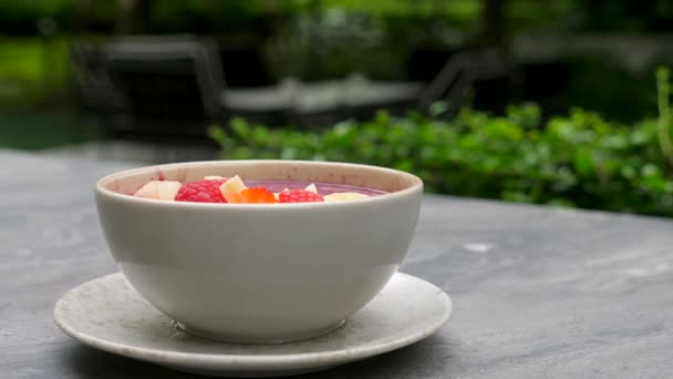 Bol à smoothie acai sain sur table en pierre dans un restaurant ou un café de luxe en plein air — Video