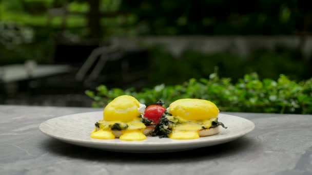 Healthy, nutritious breakfast. Fresh eggs Benedict on bun with green spinach — Stock Video