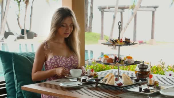 Kobieta pije gorącą kawę i delektuje się słodką piekarnią na tropikalnych wakacjach hotelowych — Wideo stockowe