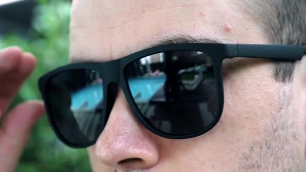 Közelkép az ember húzza le a fekete napszemüveg, bujkáló bosszús vörös vér szem — Stock videók