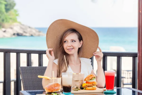 Mujer viajera con comida rápida, hamburguesas, café y jugos en el café al aire libre — Foto de Stock