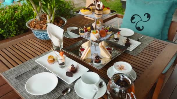 Tea set and coffee with assortment of pastries in outdoor cafe. Sweet breakfast — Stock Video