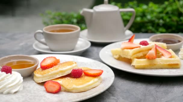 Солодка їжа на сніданок в готелі. Тарілки млинців і вафель з ягодами — стокове відео