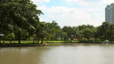 Yaz günü gökdelenleri olan yeşil şehir parkı. İnsanlar rahatlar ve rahatlar.