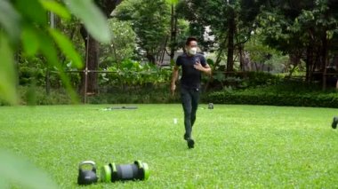 Yüz maskesi takan kişisel Asyalı fitness eğitmeni bir bayan müşteriyi motive eder.