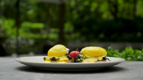 Healthy breakfast. Eggs Benedict on muffin buns with green spinach and vegetable — Stock Video