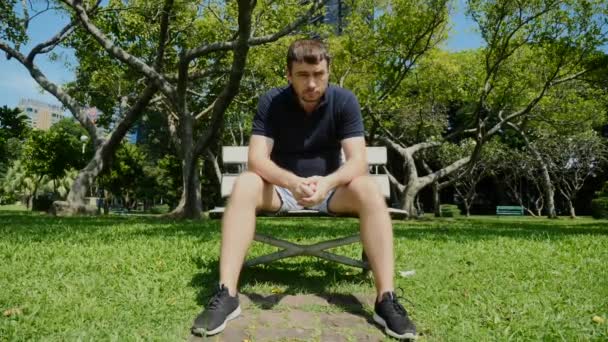 Smutný muž sedící na lavičce v městském parku, přemýšlející, ustaraný, sklíčený — Stock video