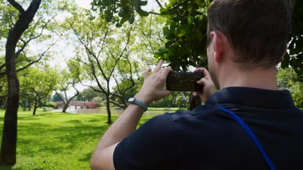 Hombre bloguero de viajes grabación de vídeo en el teléfono móvil, de pie en la naturaleza — Vídeos de Stock