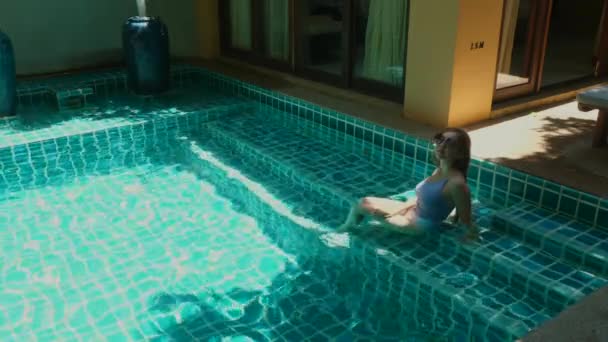 Voyageur touriste féminine en maillot de bain se détendre dans la piscine sur les vacances tropicales — Video