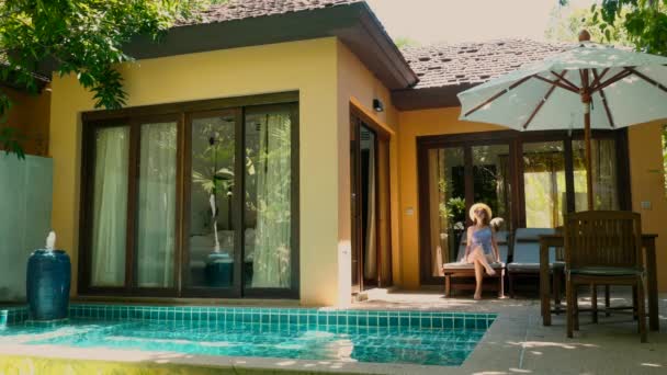Жінка-мандрівник приймає сонячні ванни на шезлонгу на терасі в готельному курорті Вілла — стокове відео